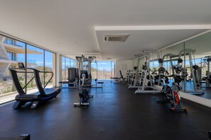 A gym with various exercise equipment, large windows, and a view of the outdoors. - Charming Coastal Resort With Ocean Views, Pool, Gym and Shared Amenities (Cabo San Lucas)