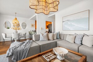 Ein modernes Wohnzimmer mit Ecksofa, einem Essbereich und einer Küche im Hintergrund.