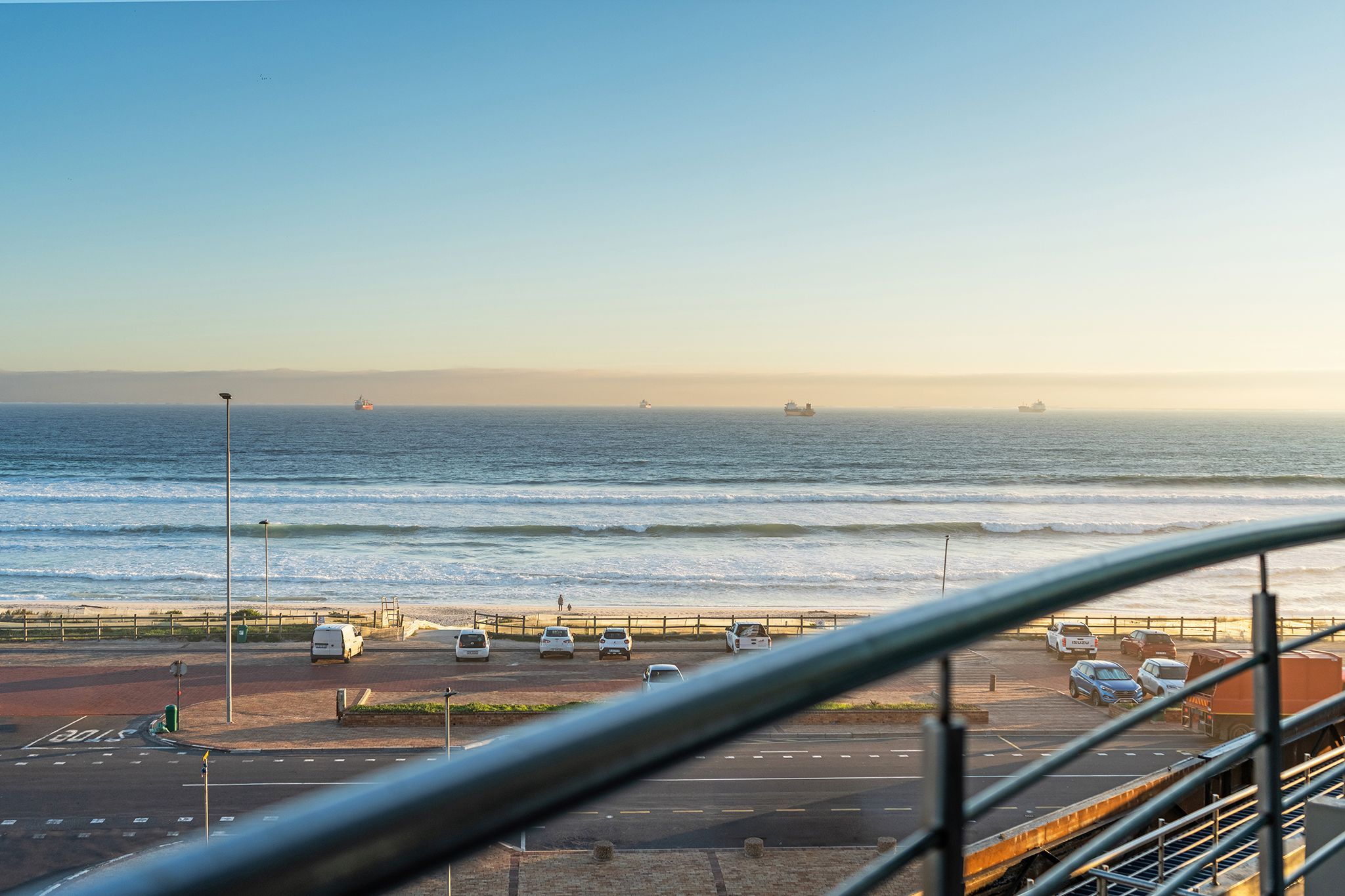 A coastal view with a parking area, a road, and the ocean.