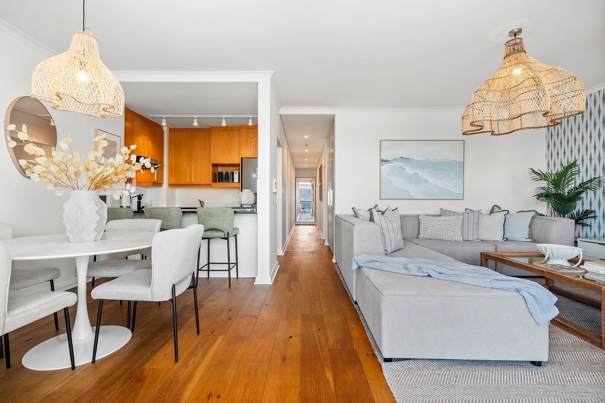 A modern living room with a sofa, dining table, and kitchen in the background.