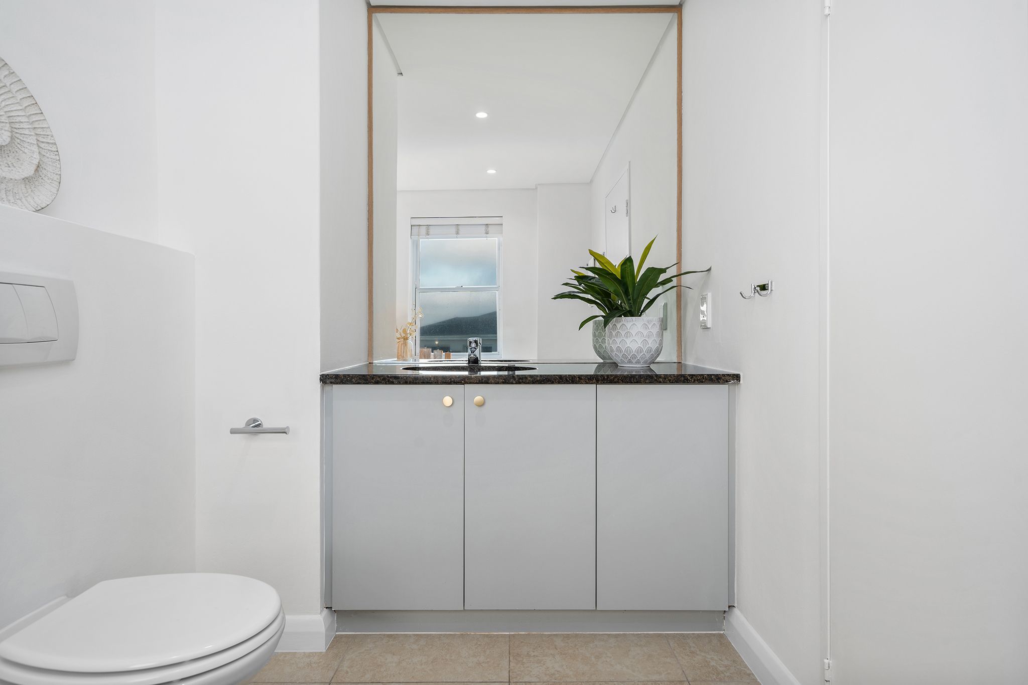 Een moderne badkamer met toilet, wastafel en spiegel.