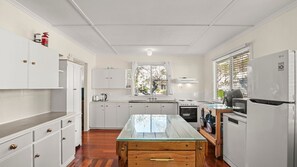 A modern kitchen with white cabinetry, a glass-top island, a stove, and a refrigerator. - Kitchener Street 2, Golden Beach (Golden Beach)