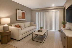 A modern living room with a sofa, coffee table, lamp, and artwork on the wall. - Montvale Urban Suites (Toronto)