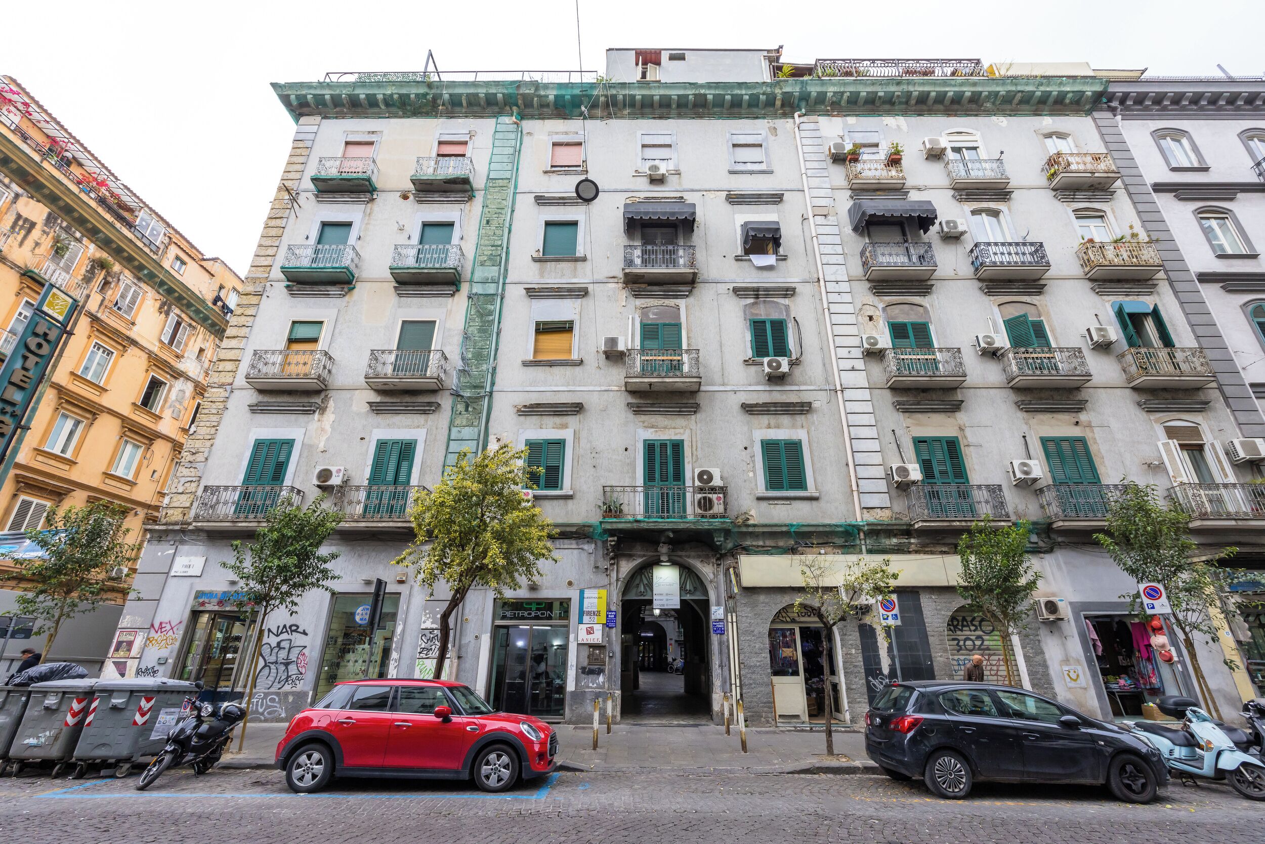 A multi-story building with balconies, a ground entrance, and a visible storefront.