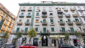 A multi-story building with balconies, a ground entrance, and a visible storefront. - Central Station Housing Apartment1 (Naples)