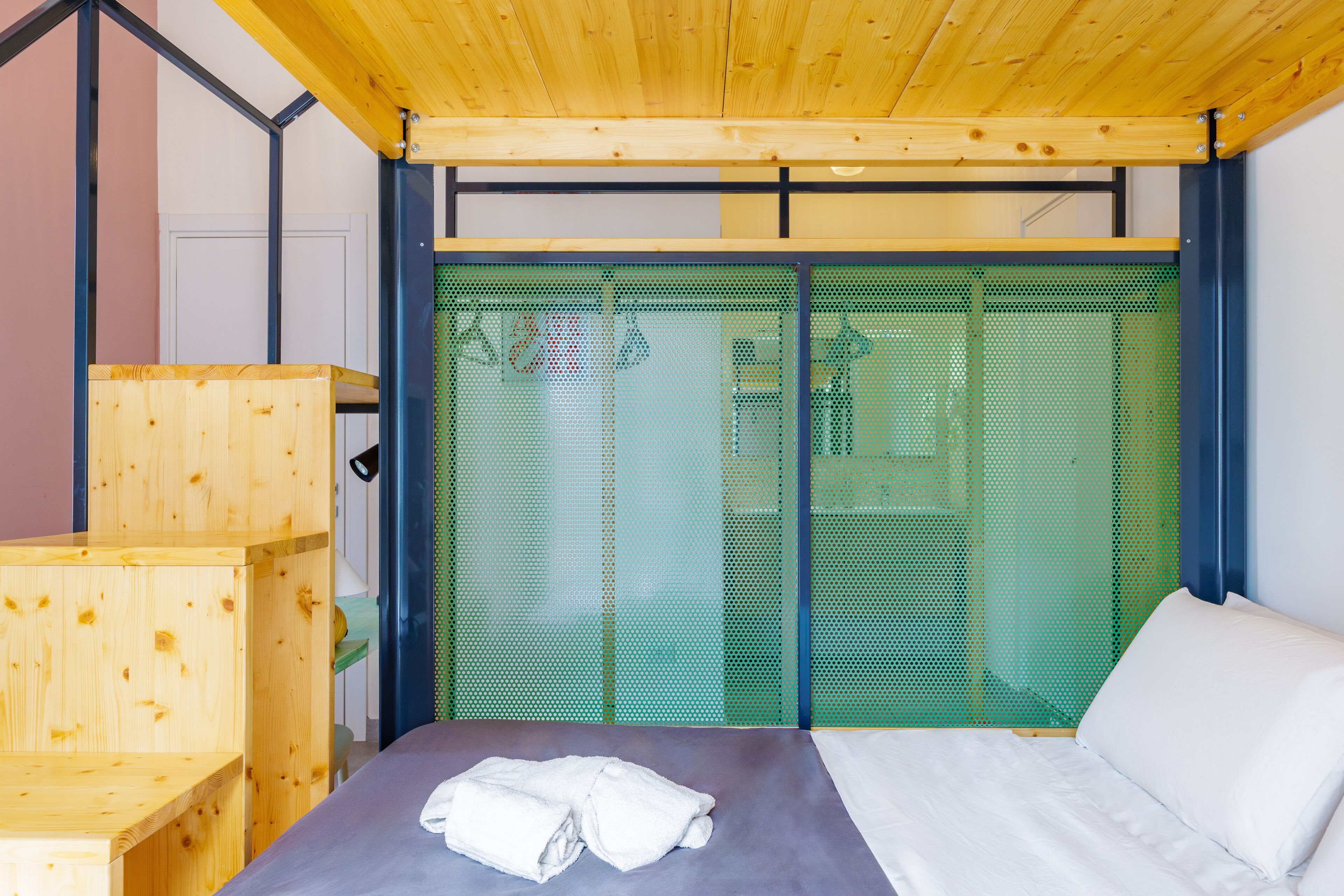 A room with a bed, wooden furniture, and a green mesh partition.