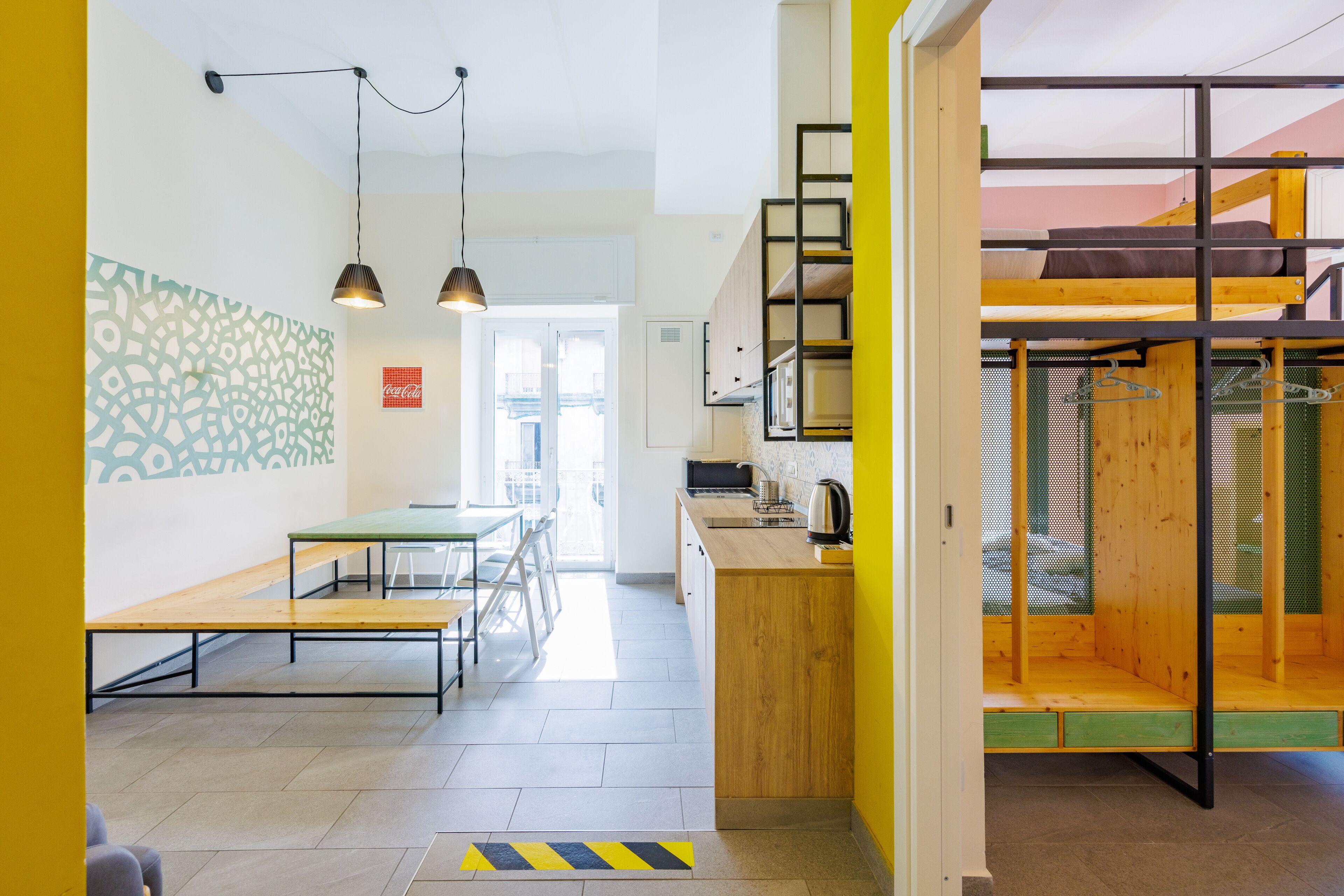 A modern interior with a dining area, kitchen, and a loft bedroom with a wooden ladder.
