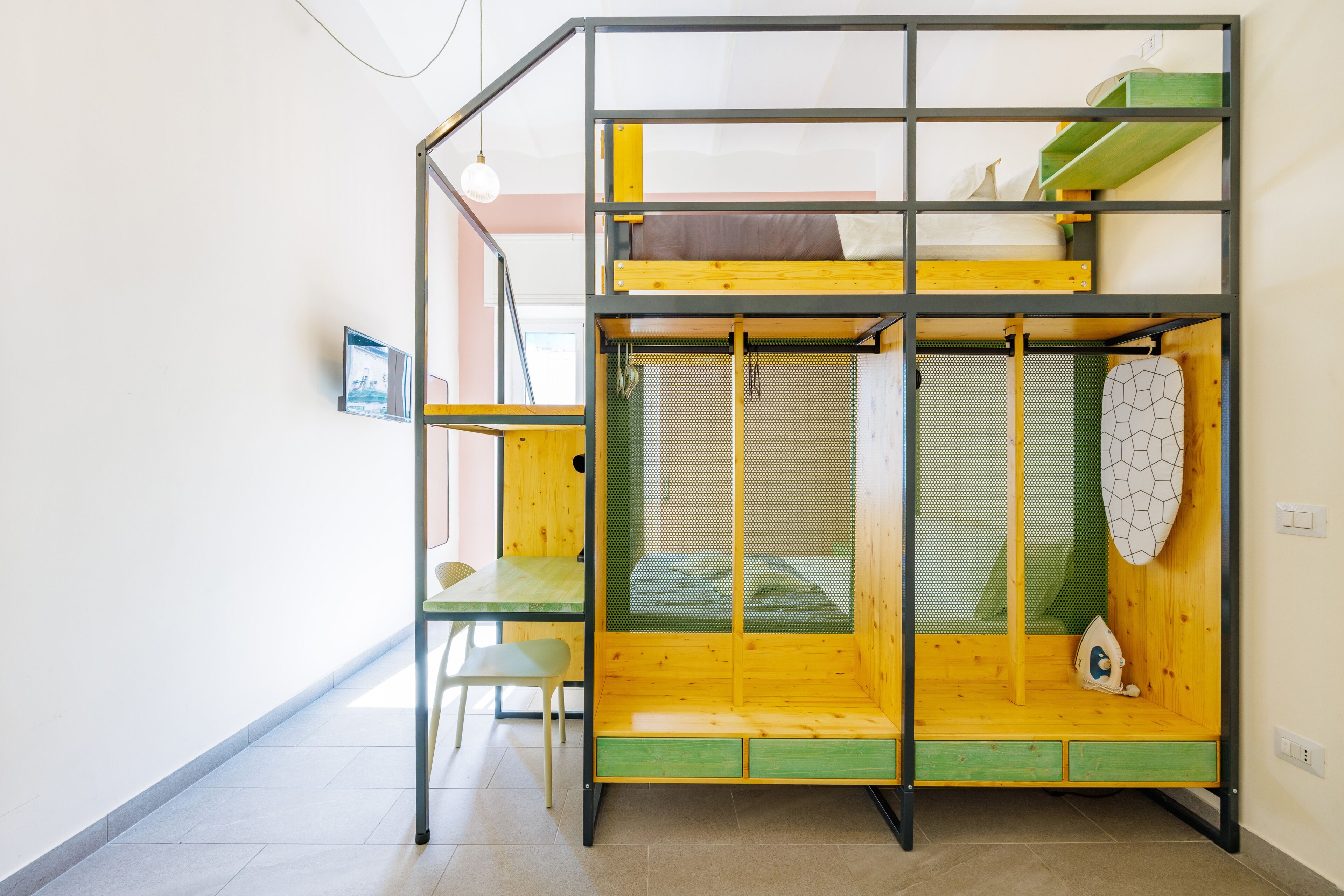 A bunk bed with a green and yellow color scheme, a small table, and a chair.