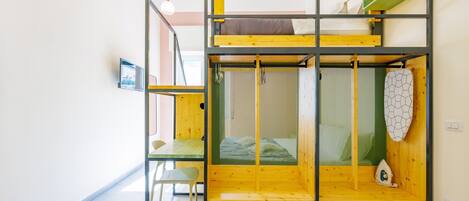 A bunk bed with a green and yellow color scheme, a small table, and a chair.