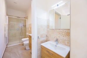 Ein Badezimmer mit Dusche, Toilette, Waschbecken und Spiegel.