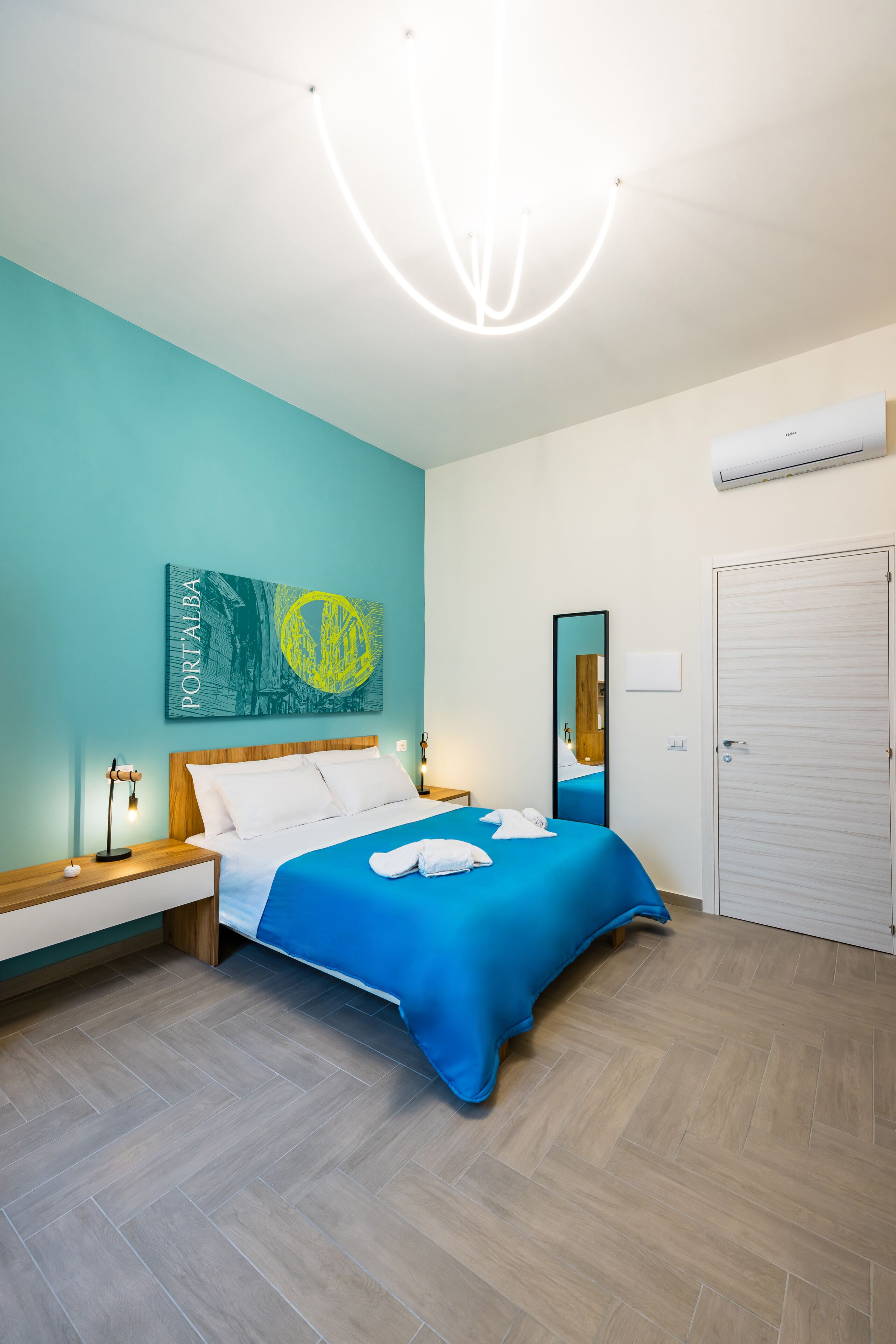 Une chambre à coucher moderne avec un lit, des tables de chevet, un miroir et une porte.