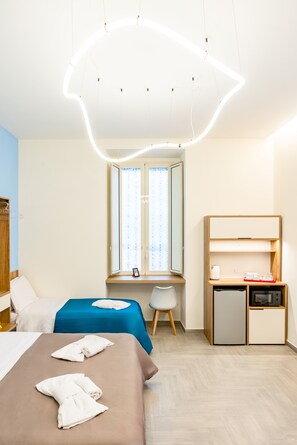 A hotel room with a bed, a desk, a chair, a wardrobe, and a small kitchenette. - Solaris Suites by Napoliapartments (Naples)