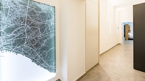 Un pasillo con un mapa grande en la pared, suelo de madera y una puerta que da a otra habitación.