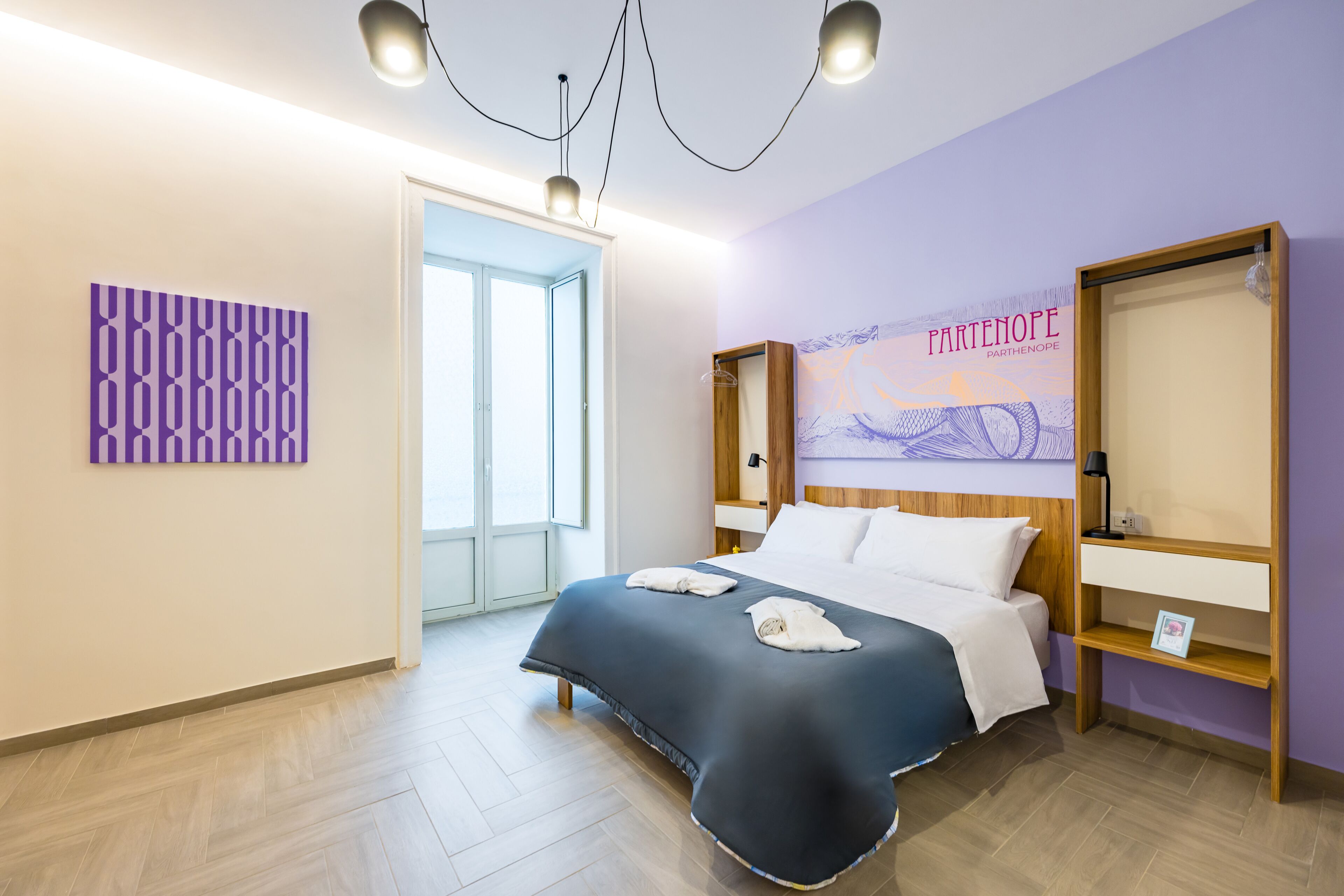 Quarto de hotel com uma cama, cabeceira de madeira, televisão fixada na parede e porta que dá para um banheiro.