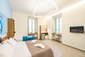 A hotel room with a bed, a desk, a TV, and a kitchenette. - Solaris Suites by Napoliapartments (Naples)