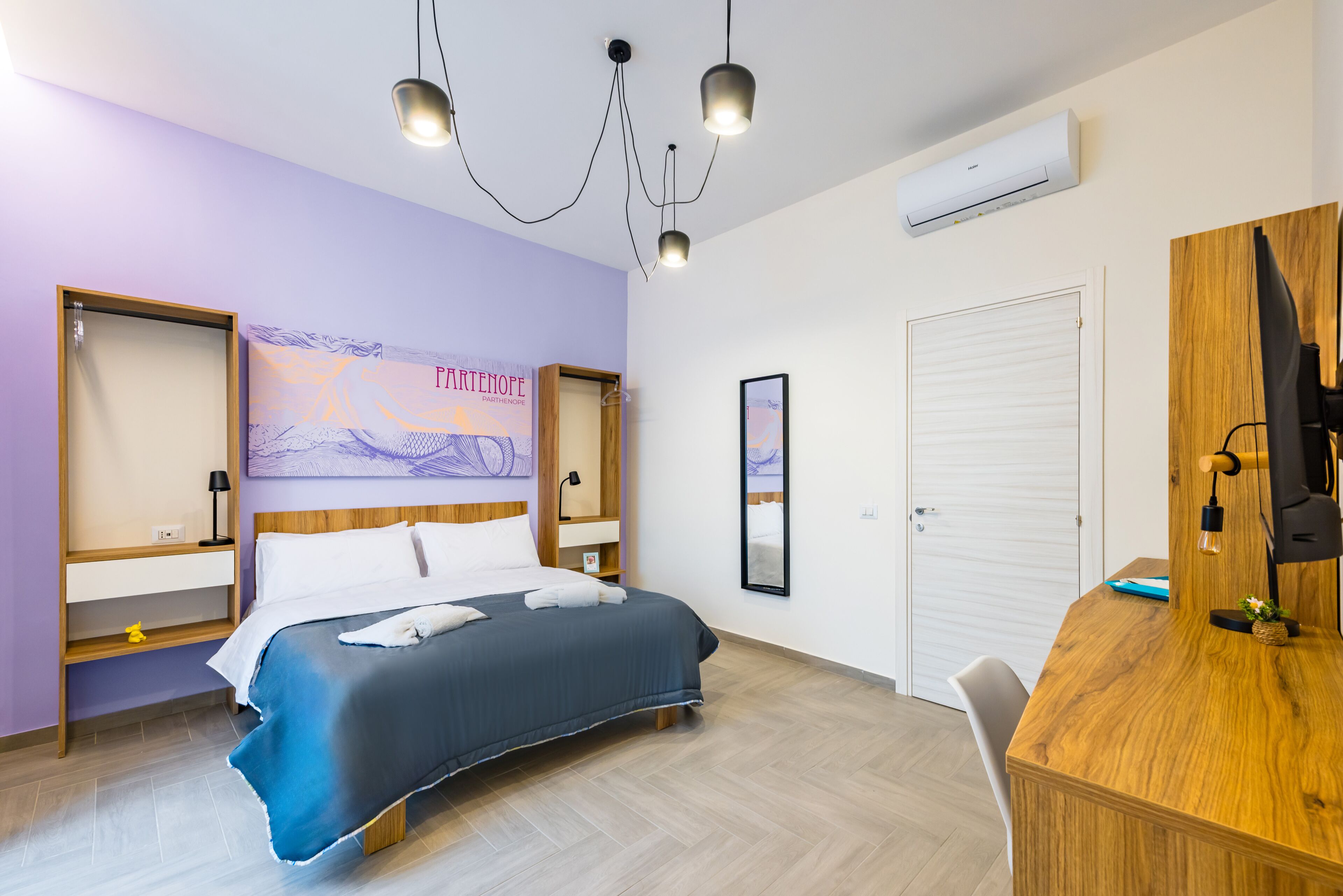 A hotel room with a bed, desk, and wardrobe.