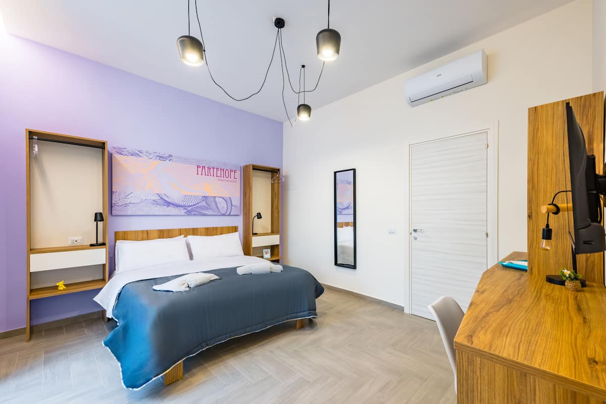 A hotel room with a bed, desk, and wardrobe.