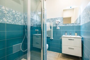 A bathroom with a glass shower enclosure, a white sink, and a mirror above the sink. - Glow Tripla - Solaris Suites (Naples)