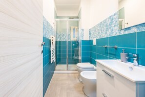A bathroom with a shower, toilet, and sink, featuring blue and white tiles. - Solaris Suites by Napoliapartments (Naples)