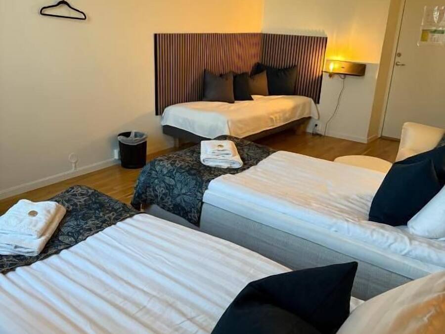 Une chambre d’hôtel avec deux lits, une table de chevet, une lampe et une porte.
