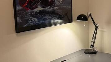 A desk with a framed artwork, a desk lamp, and a piece of paper.