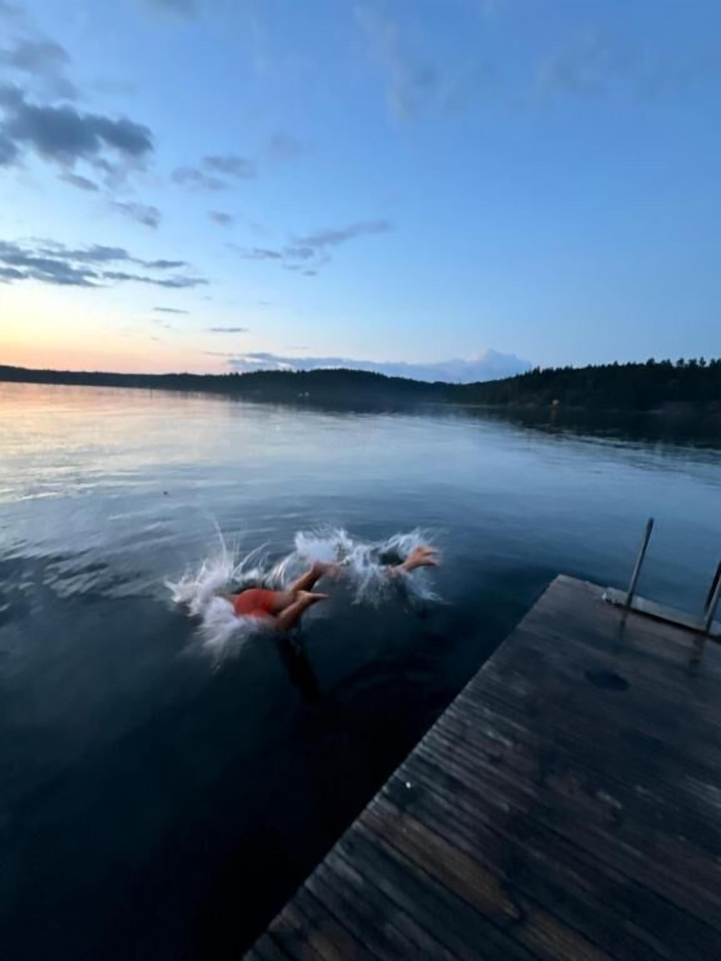 Een houten steiger die uitsteekt in kalm water, met een heldere lucht erboven.
