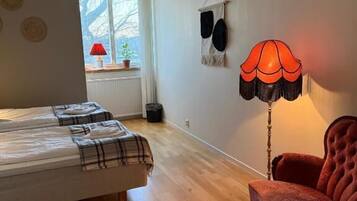 Una habitación con una cama, un sillón rojo, una lámpara y una ventana con vistas.