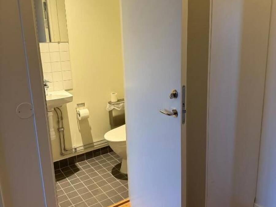 A bathroom with a toilet, sink, and tiled floor.