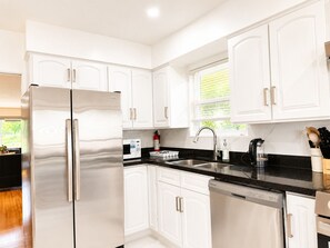 A modern kitchen with white cabinetry, stainless steel appliances, and a black countertop. - Park View 3BR Home.Covered SunDeck. Near Metrotown (Vancouver)