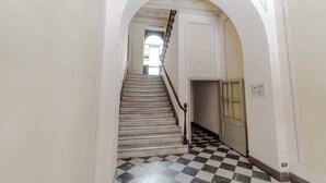 Una escalera con piso a cuadros, barandilla y una puerta con panel de vidrio satinado.