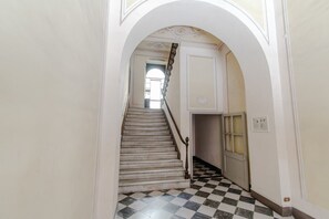 Eine Treppe mit Schachbrettmuster, einem Geländer und einer Tür mit Milchglasfenster.