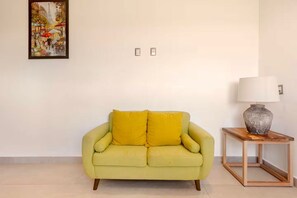 A room with a green sofa, a lamp on a wooden side table, and a painting on the wall. - Akbal Cancun (Cancún)