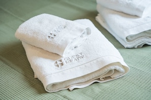 A stack of white towels with embroidered text, placed on a textured surface. - GuestReady - Studio in São Mamede de Infesta (São Mamede de Infesta)