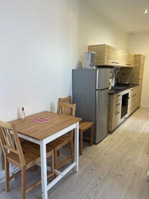 Eine kleine Küche mit Kühlschrank, Spüle und Holzschränken.