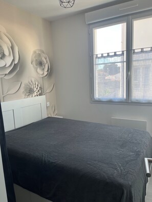 Ein Schlafzimmer mit einem Bett, einem Fenster mit Aussicht und einer Wand mit floralem Dekor.