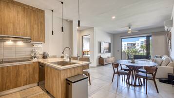 A modern kitchen with wooden cabinets, a central island, and a dining area with a round table and chairs.