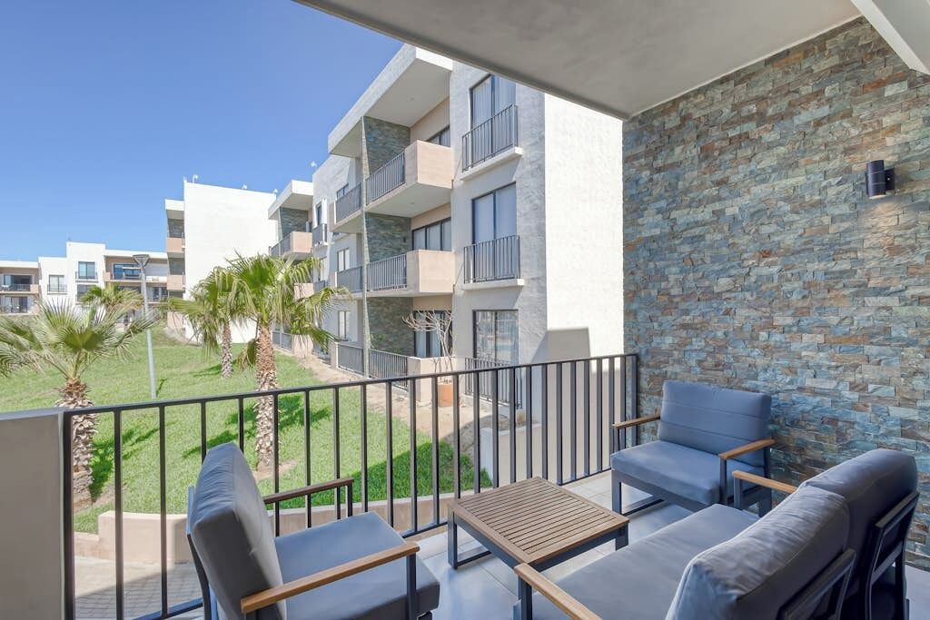 Ein Balkon mit Sitzgelegenheit, einer Steinmauer und Blick auf angrenzende Gebäude.