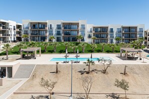 Un hotel moderno con piscina, area salotto esterna e palme.