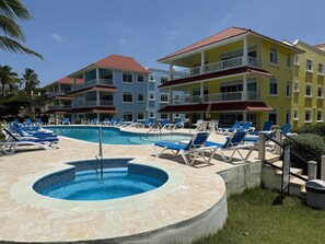 Un complexe hôtelier doté d’une piscine, de chaises longues et de bâtiments à plusieurs étages.