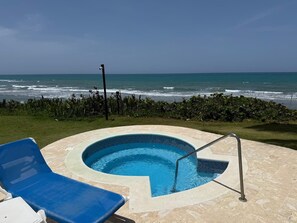 Une piscine avec vue sur l’océan, un mât pour drapeau et une haie.