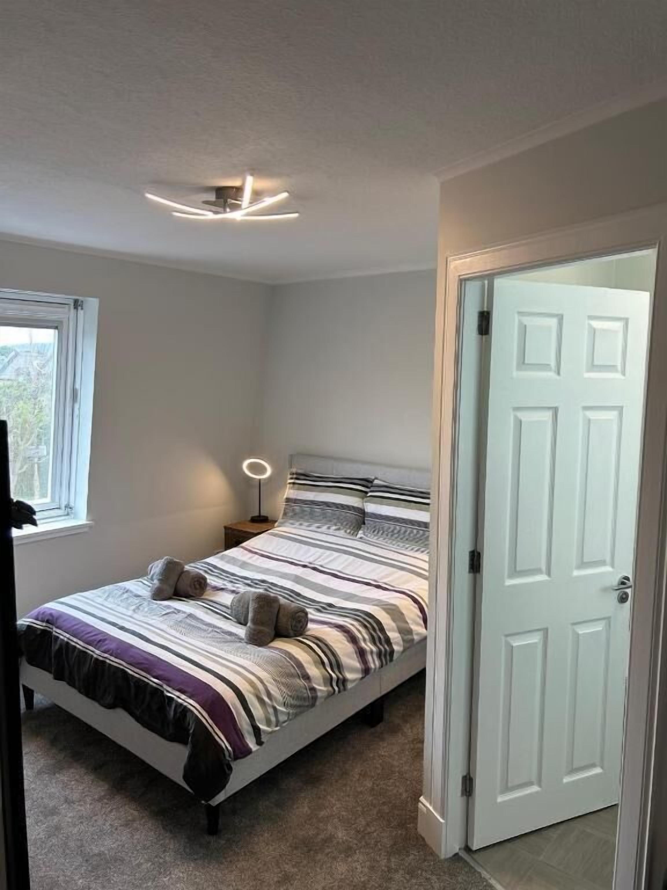 Una camera da letto con un letto, una lampada da comodino e una porta.