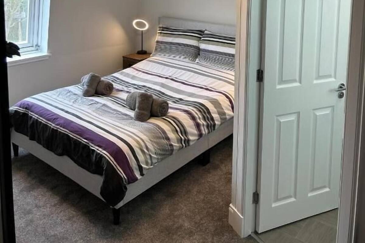 A bedroom with a bed, bedside lamp, and a door.