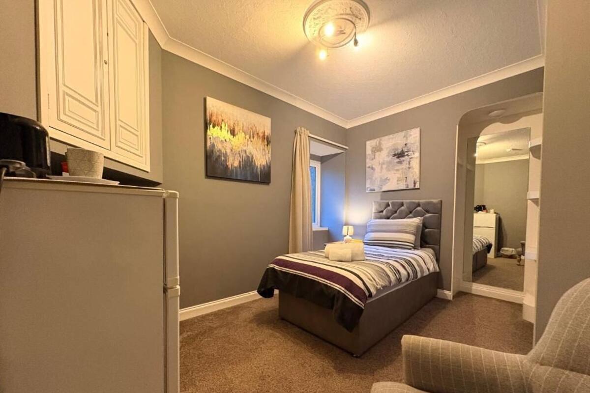 A bedroom with a bed, a chair, a dresser, and a painting on the wall.