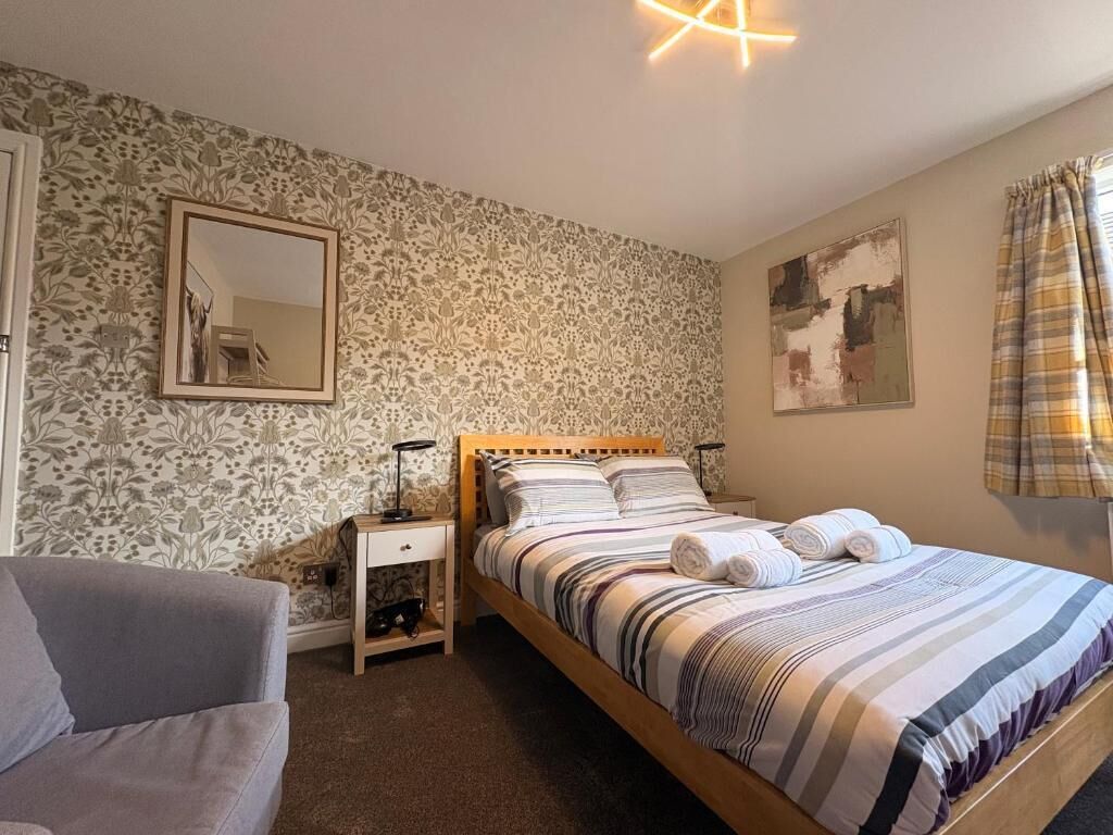 Una camera da letto con un letto, comodini, uno specchio e una finestra con tende.