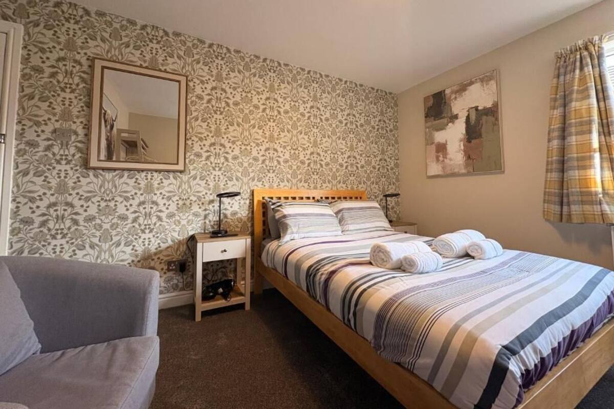 A bedroom with a bed, bedside tables, a mirror, and a window with curtains.