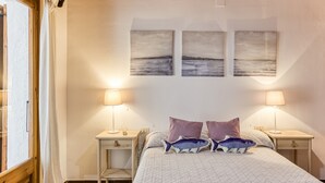 A bedroom with a bed, two bedside tables, a nightstand, and three wall-mounted pictures.