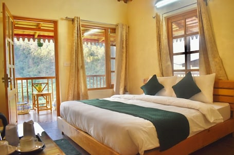 A bedroom with a wooden bed, a balcony, and a view of the forest.. The Peach Hillside Kainchi Dham