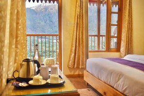 A room with a bed, a table with a tray of tea items, and a window with curtains.
