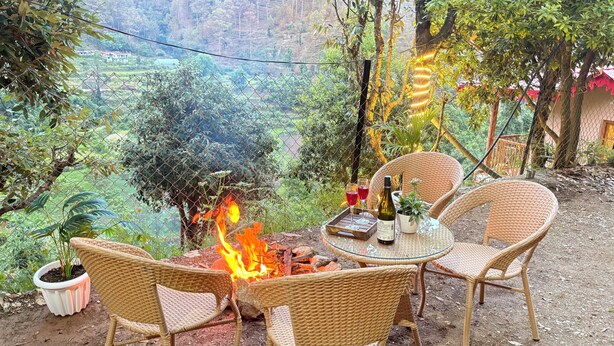 Una mesa de mimbre con sillas, un fuego y vistas a un valle.