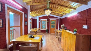 Un interior rústico de madera con techo alto, mesas de madera, sillas de mimbre y una araña.